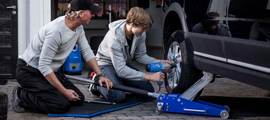 To personer skifter hjul på en bil.