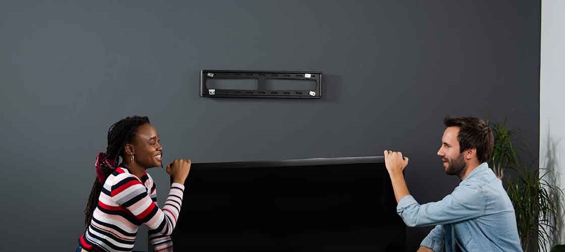 En kvinne og en mann flytter på plass en tv