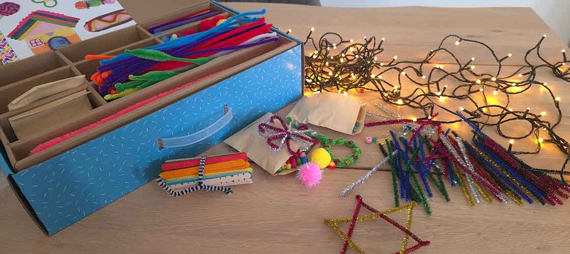 Creative craft table featuring supplies from the craft box—colorful pipe cleaners, popsicle sticks, pom-poms, and string lights—for creative projects.