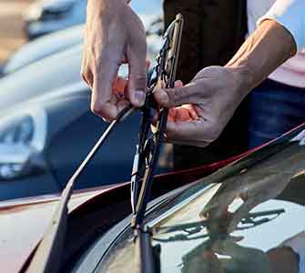 A pair of hands are installing wiper blades on a car.